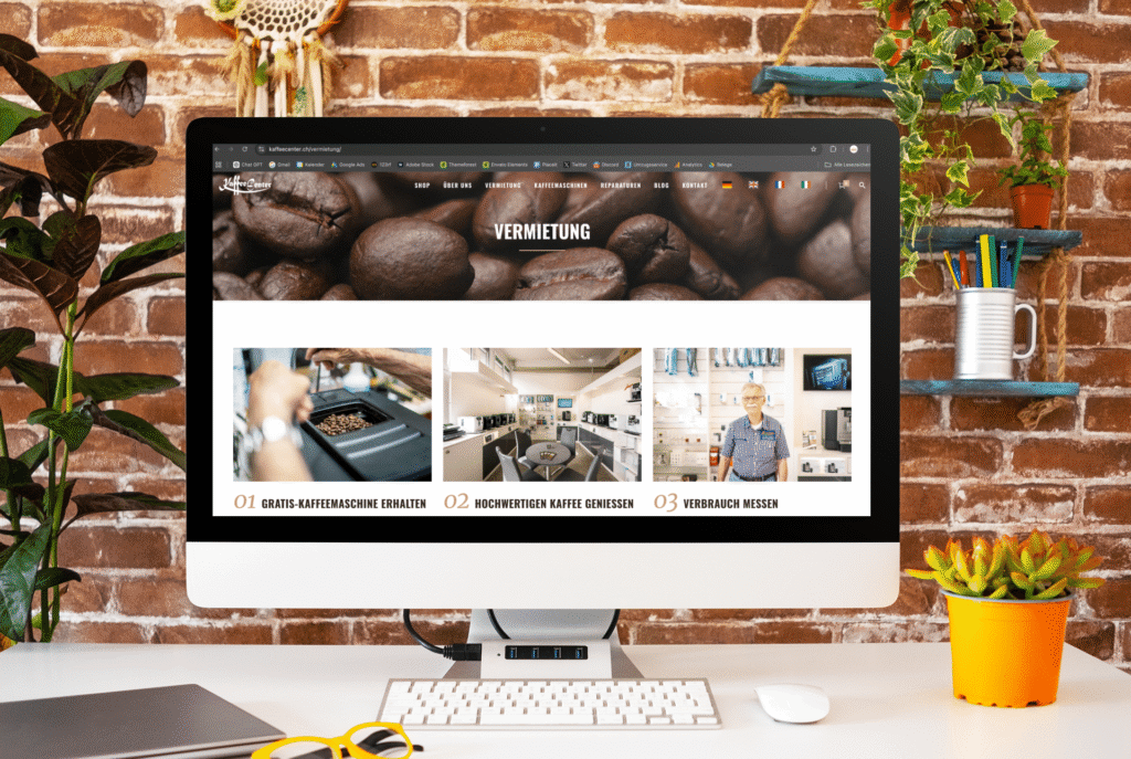 An iMac in front of a brick wall, with the Kaffeecenter GmbH rental page and three steps