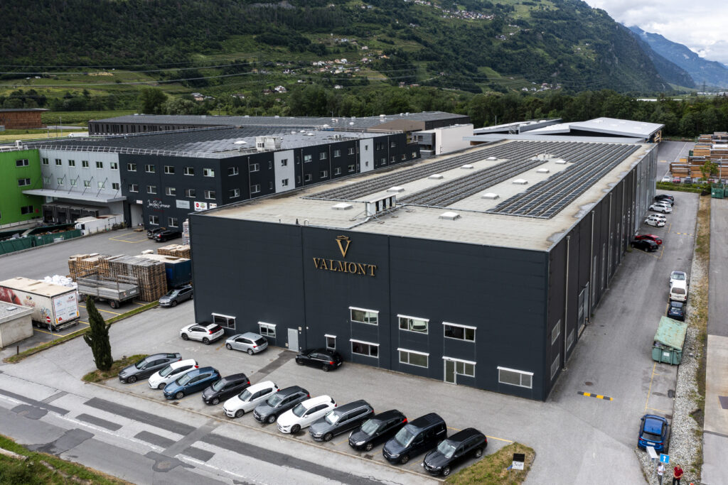 Aerial view of the Westgate site in Vétroz, showing a dark industrial building, the Valmont logo and a solar roof