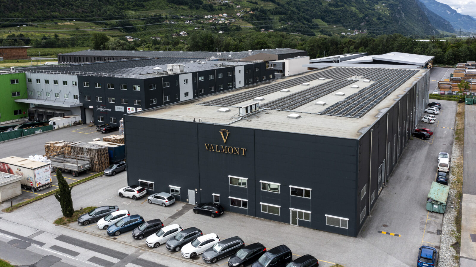 Aerial view of the Westgate site in Vétroz, showing a dark industrial building, the Valmont logo and a solar roof