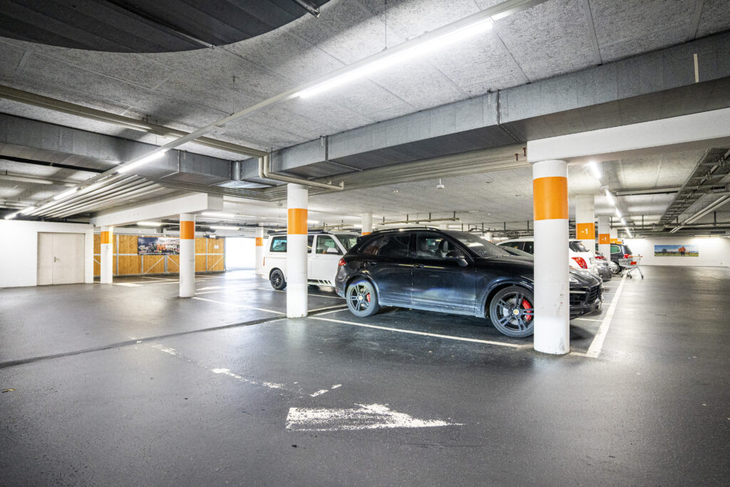Car park level in Zuchwil with orange-marked columns and parked cars