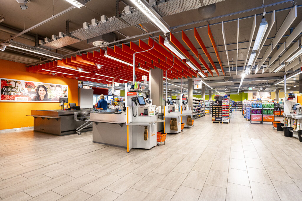 The checkout area at Migros in Zuchwil, featuring orange ceiling panels and the ‘Thank You’ wall