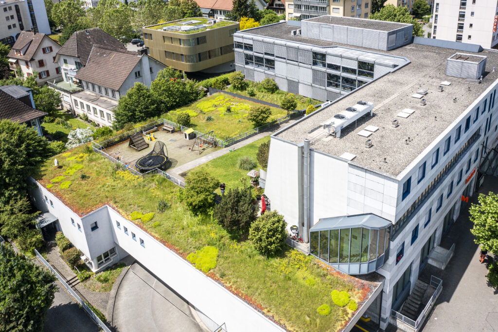 Aerial view of the roof garden in Zuchwil with a playground; the office block can be seen behind it